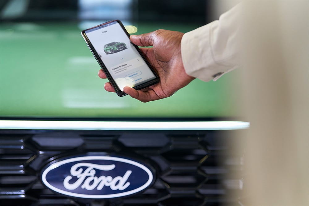 Man kijkt naar smartphone met Ford-app