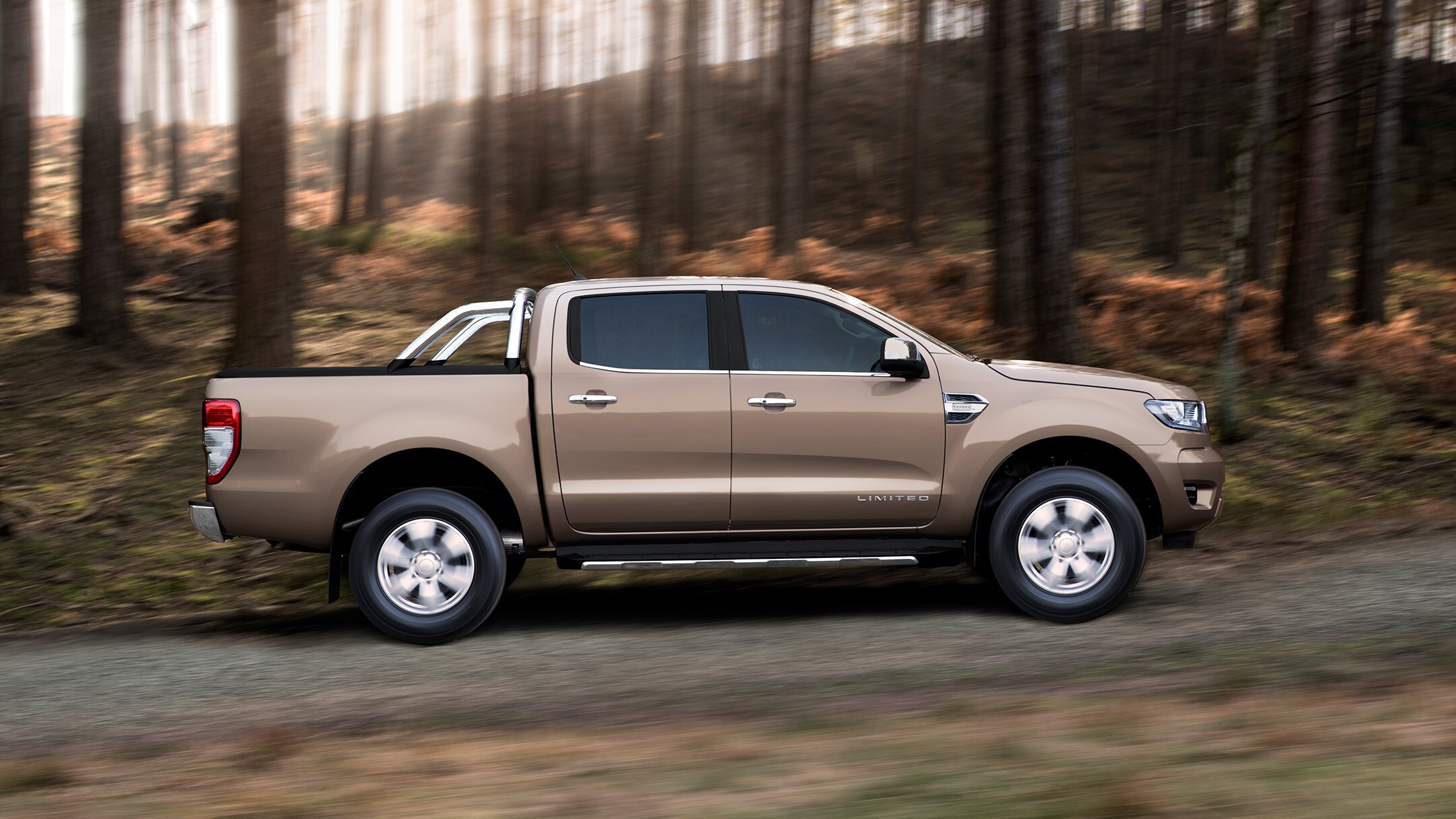 Ford Ranger Wildtrak die over een bosweg bergweg rijdt, zeven achtste vooraanzicht