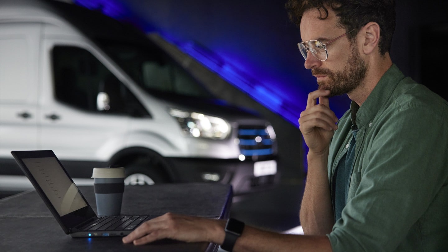Person working on laptop with Ford E-Transit at background