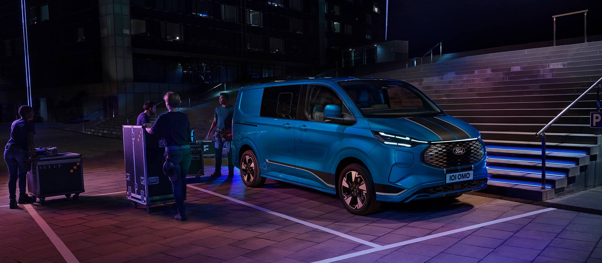 Blauwe Ford E-Transit Custom elektrische bestelwagen die's nachts wordt geladen. 