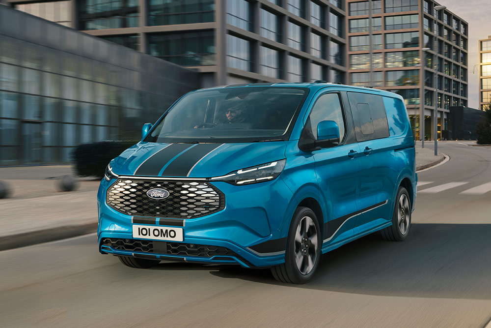 Blauwe Ford E-Transit Custom Sport Multi-use rijdt door een stadsstraat.
