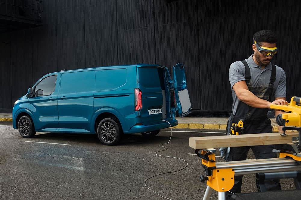 Blauwe Ford Transit Custom bestelwagen en een persoon die elektrisch gereedschap gebruikt.