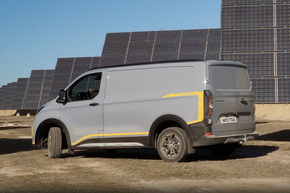 Grijze Ford Transit Custom Trail bestelwagen met gele accenten.