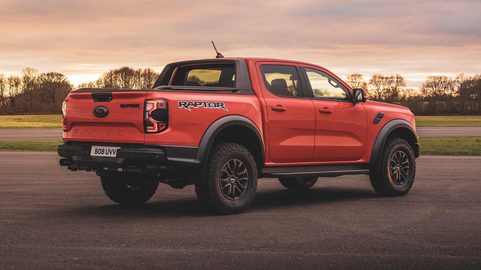 Achteraanzicht van een oranje Ford Ranger Raptor geparkeerd op een circuit.