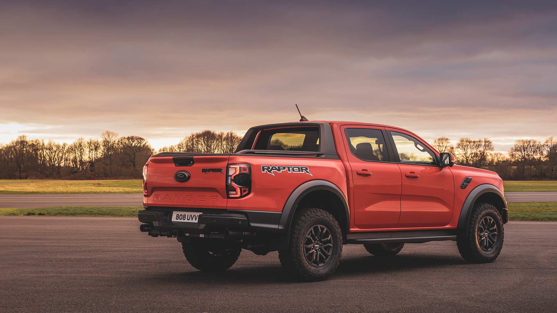 Achteraanzicht van een oranje Ford Ranger Raptor rijdend op een circuit.