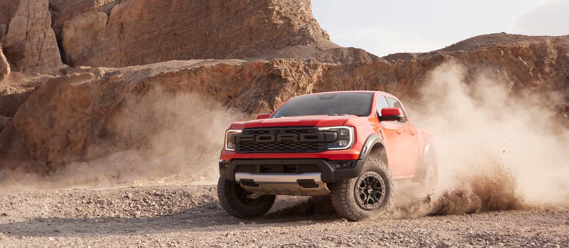 Oranje Ford Ranger Raptor rijdt door steengruis.