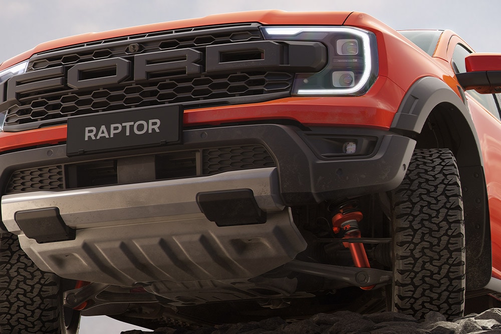 Voorkant onderzijde van een Ford Ranger Raptor in de kleur Code Orange met ophanging en voorgrille. 