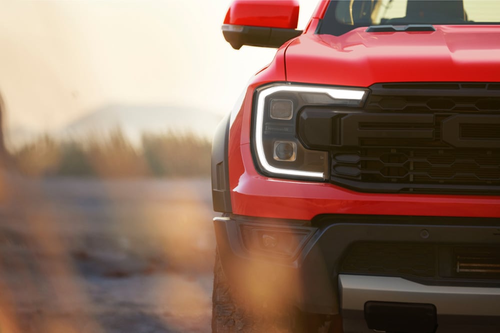 Close-up van de grille van een rode Ford Ranger Raptor.
