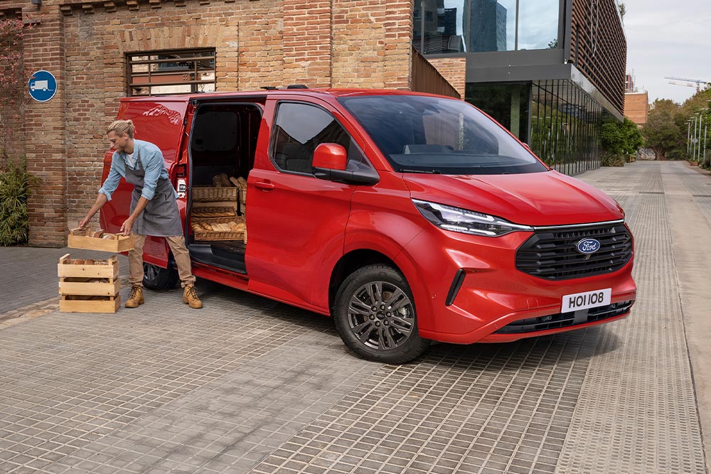 De bezorger laadt pakketten in een rode Ford Transit Custom.
