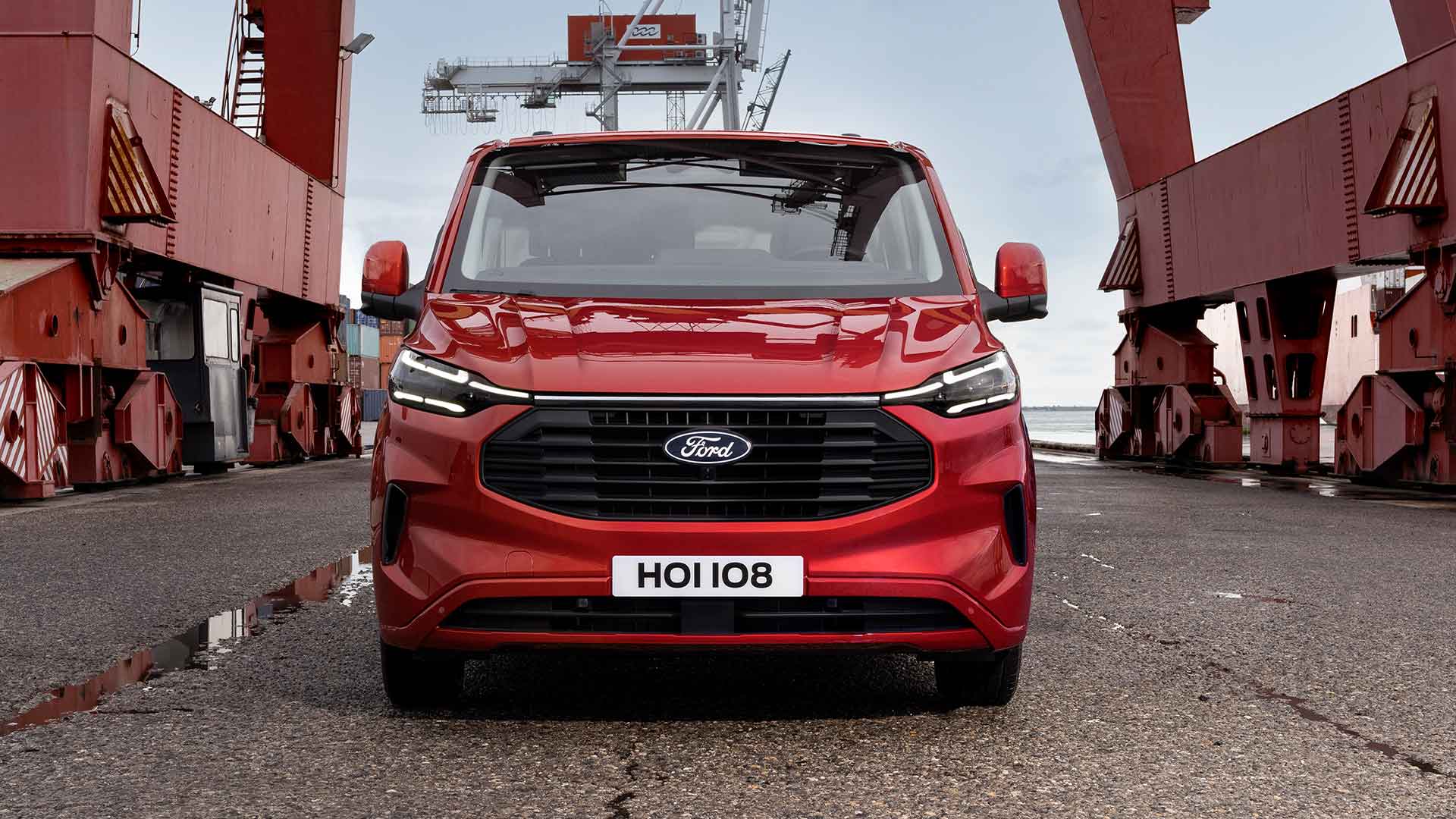 Rode Ford Transit Custom bestelwagen in een haven.