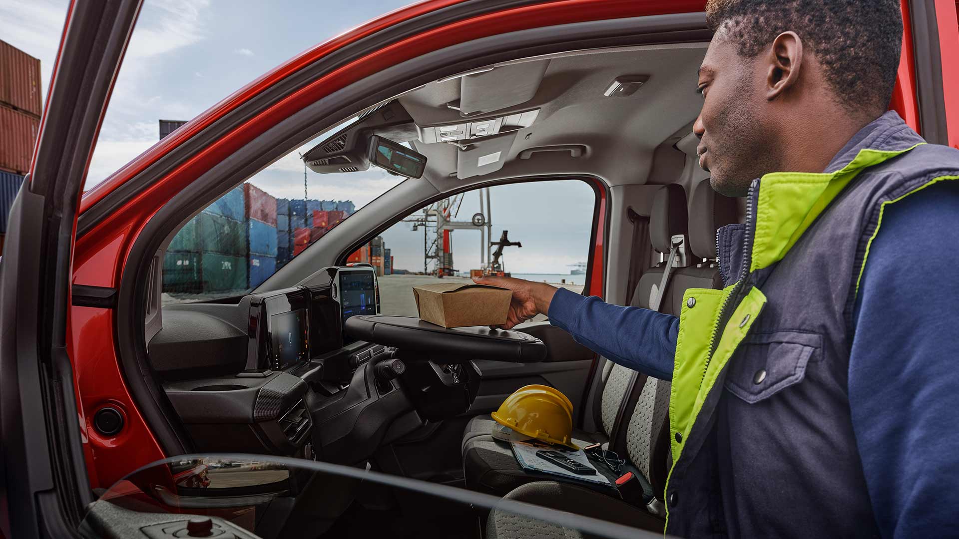 De bezorger plaatst pakketten in een rode Ford Transit Custom.
