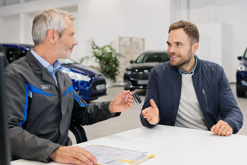 Twee mensen in gesprek bij een Ford-verdeler