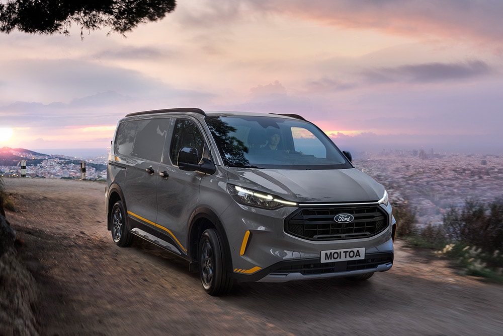 Een grijze Ford Transit Custom Trail bestelwagen met gele accenten.