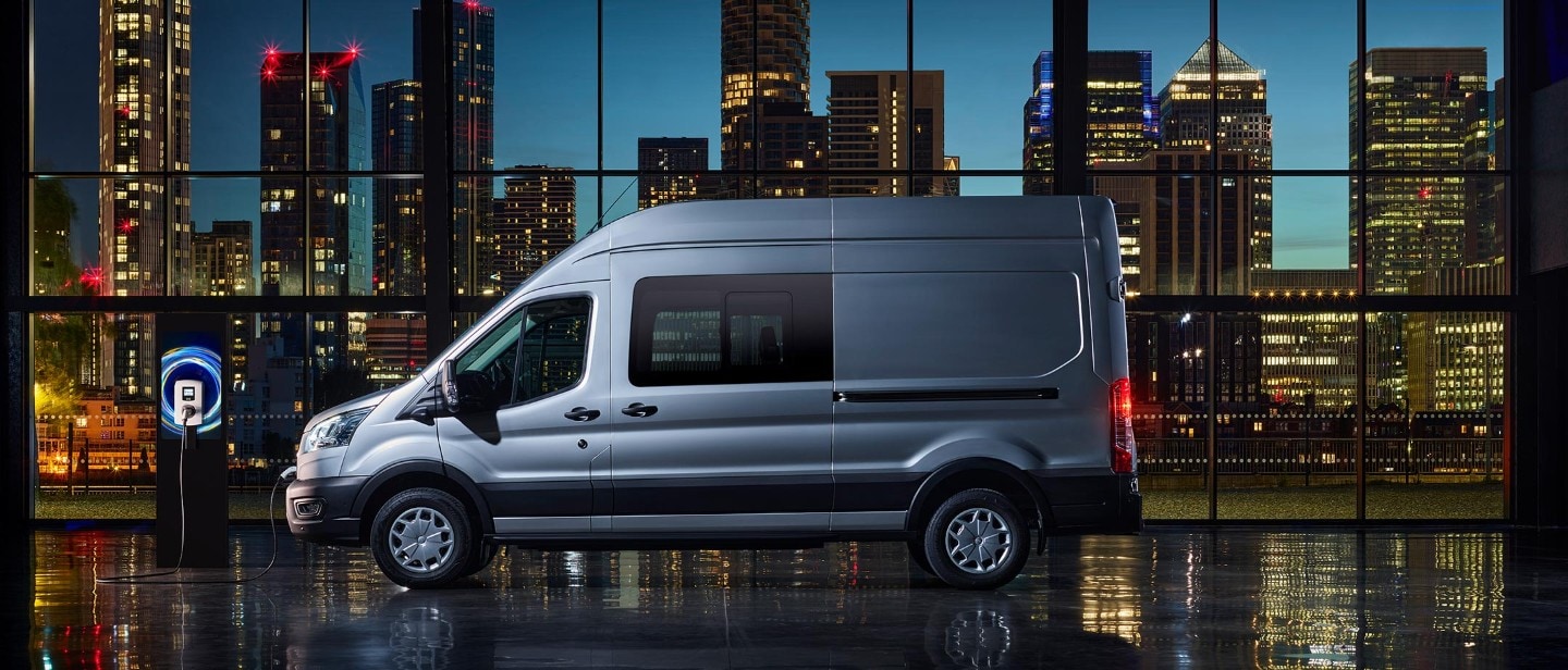 New E-Transit side view with the backdrop of city in night with blue electric lights