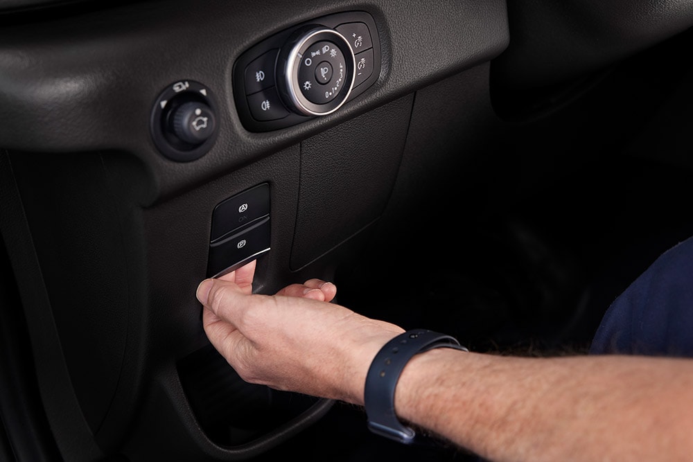 Close-up van een hand die op een knop op het dashboard van een Ford E-Transit elektrische bestelwagen drukt.