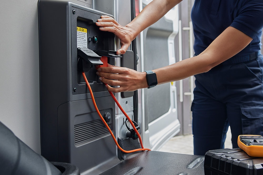 Close-up van een persoon die een oplaadkabel aansluit op een Ford E-Transit elektrische bestelwagen.
