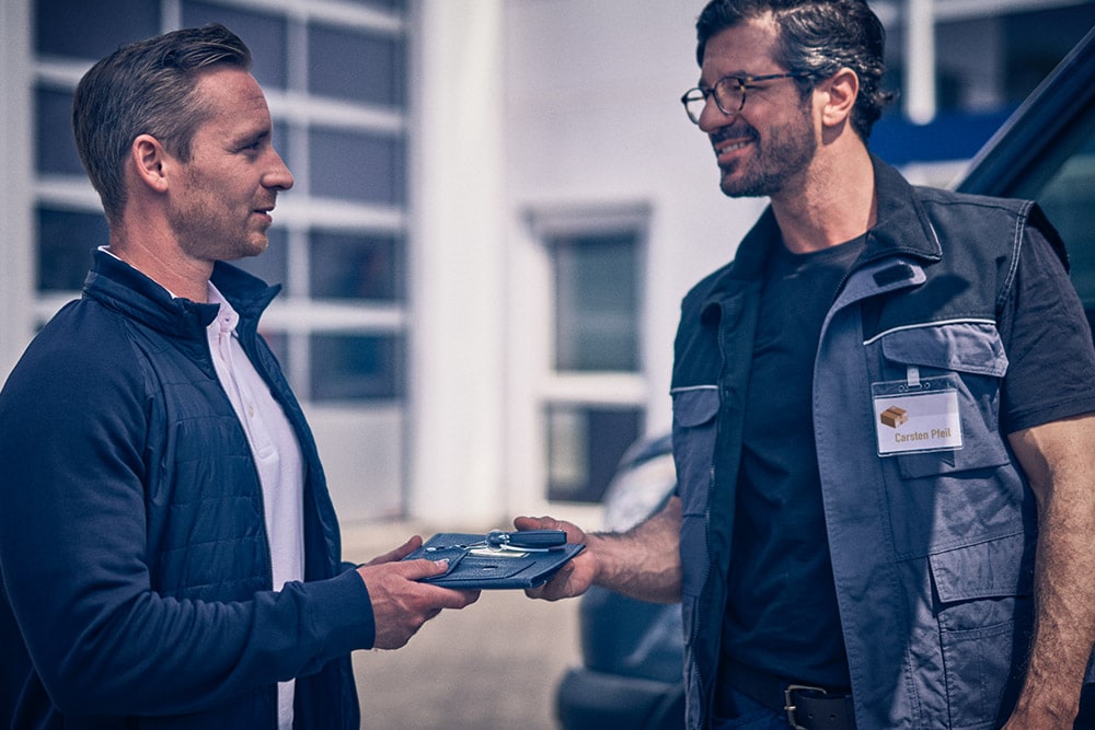 Man overhandigt een tablet aan een andere man voor een Ford Transit bestelwagen.