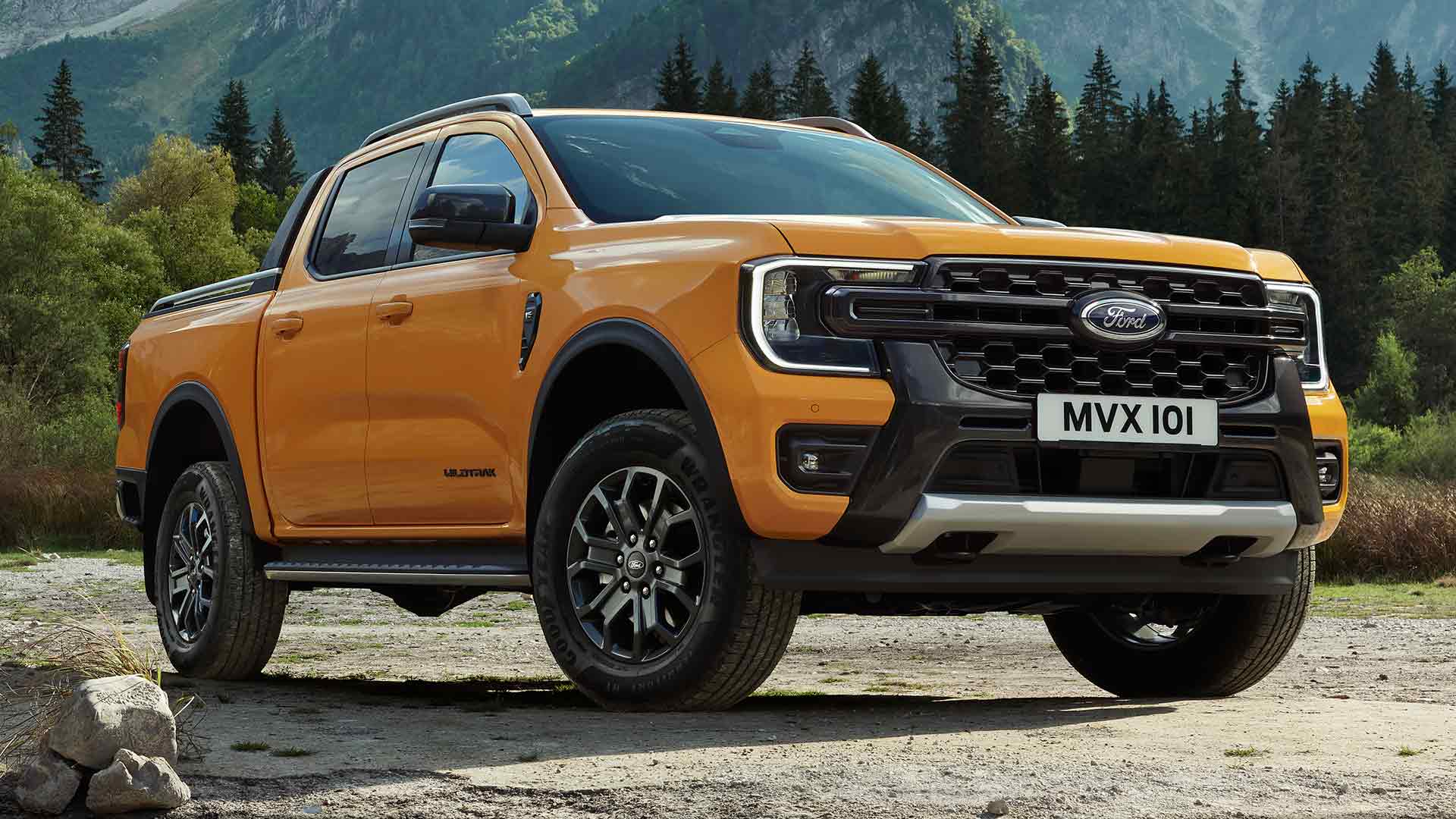 Gele Ford Ranger Wildtrak Double Cab met een schilderachtige bos- en bergachtergrond.