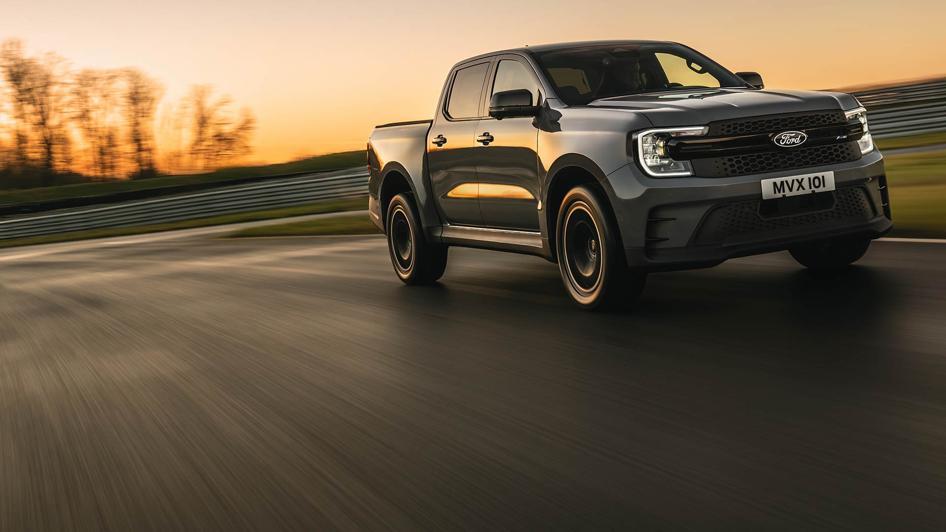 Een donkergrijze Ford Ranger Platinum bij zonsondergang op een circuit.