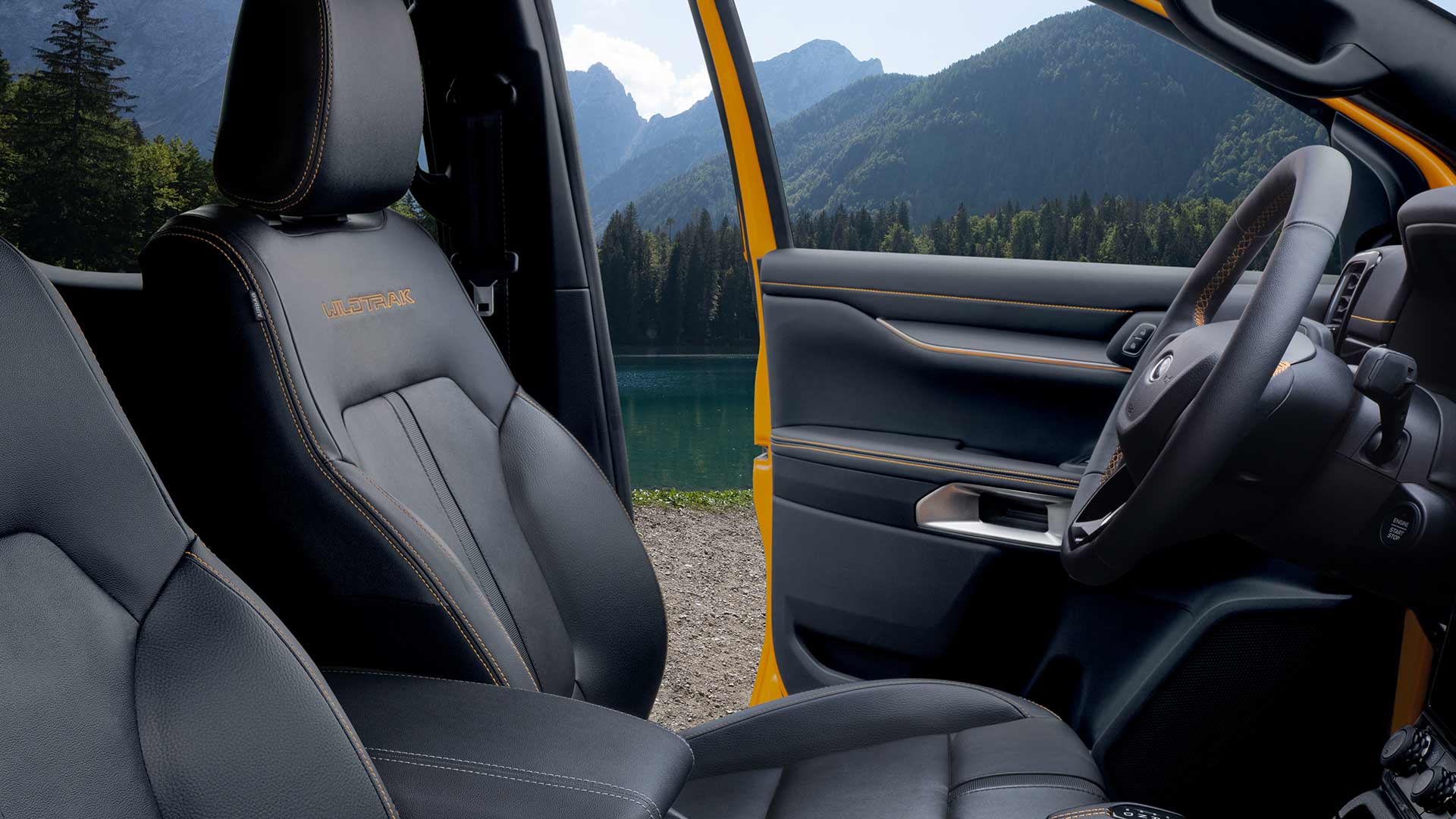 Binnenaanzicht van een Ford Ranger Wildtrak met zwarte lederen stoelen en geel 'Wildtrak'-borduursel.
