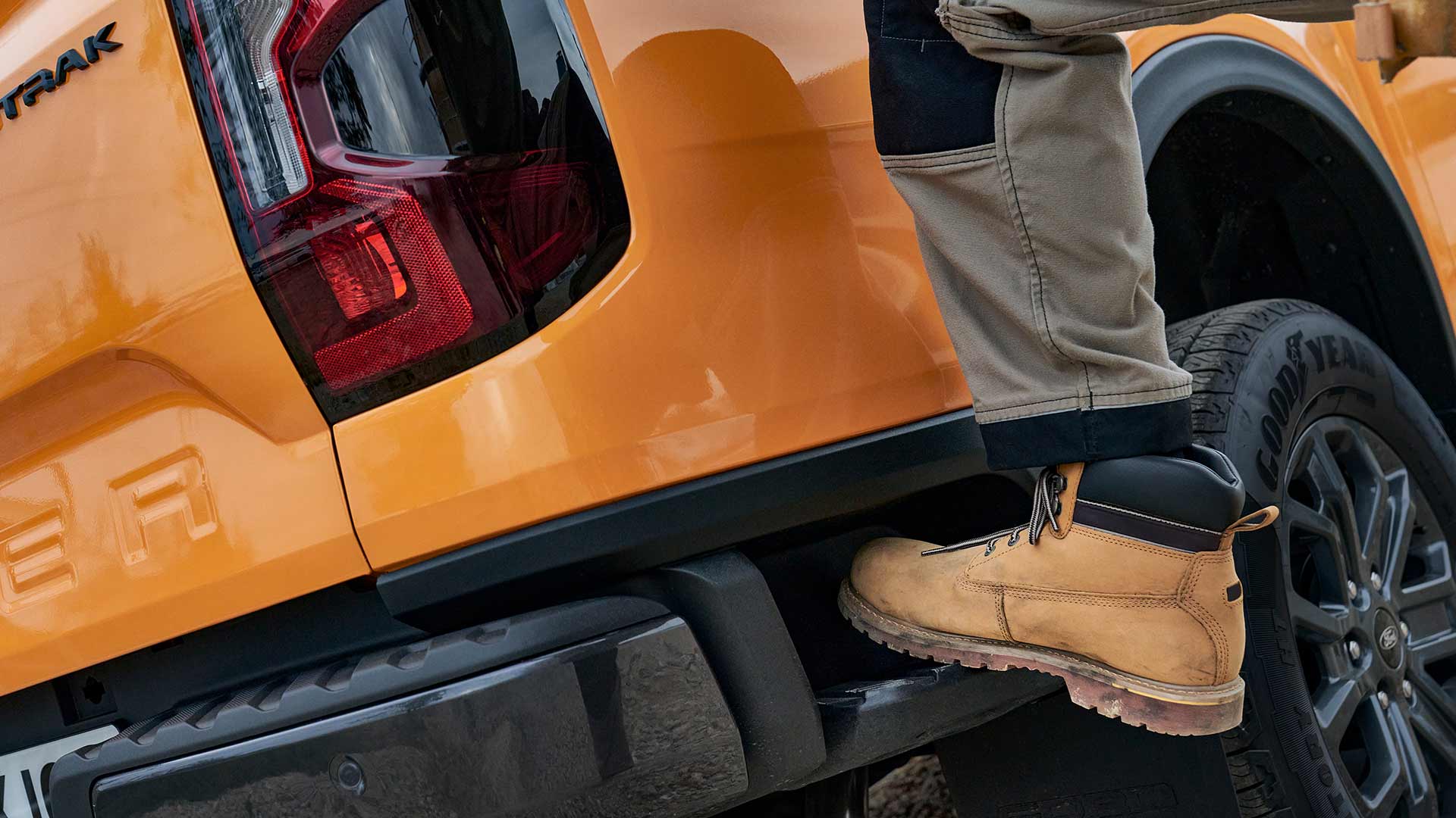 Werknemer stapt op het achterstapje van de Ford Ranger.