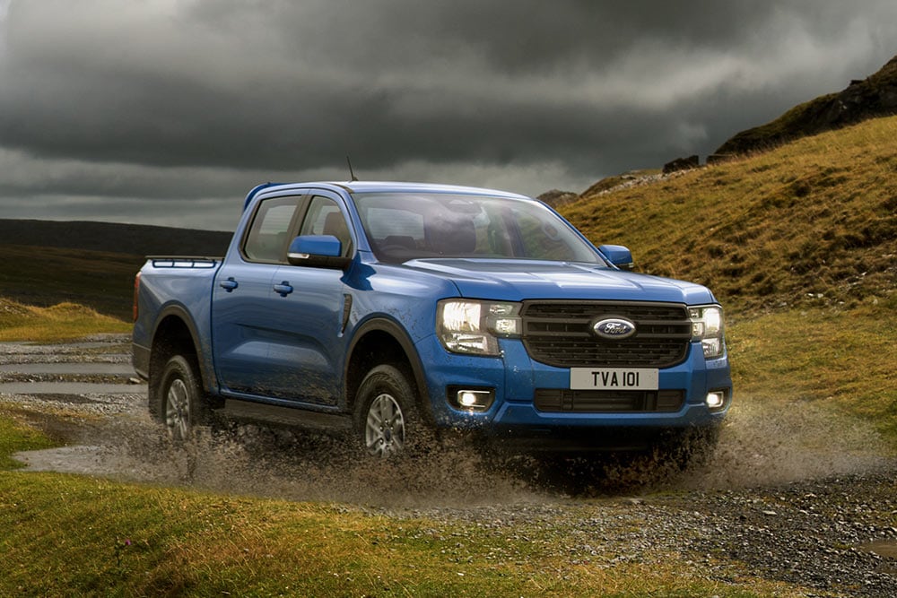 Blauwe Ford Ranger door een ruig landschap.