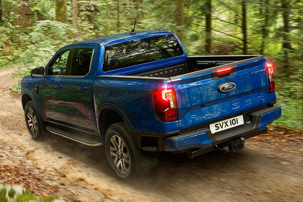 Achterlicht en achterklep van een blauwe Ford Ranger pick-up op een onverharde weg.