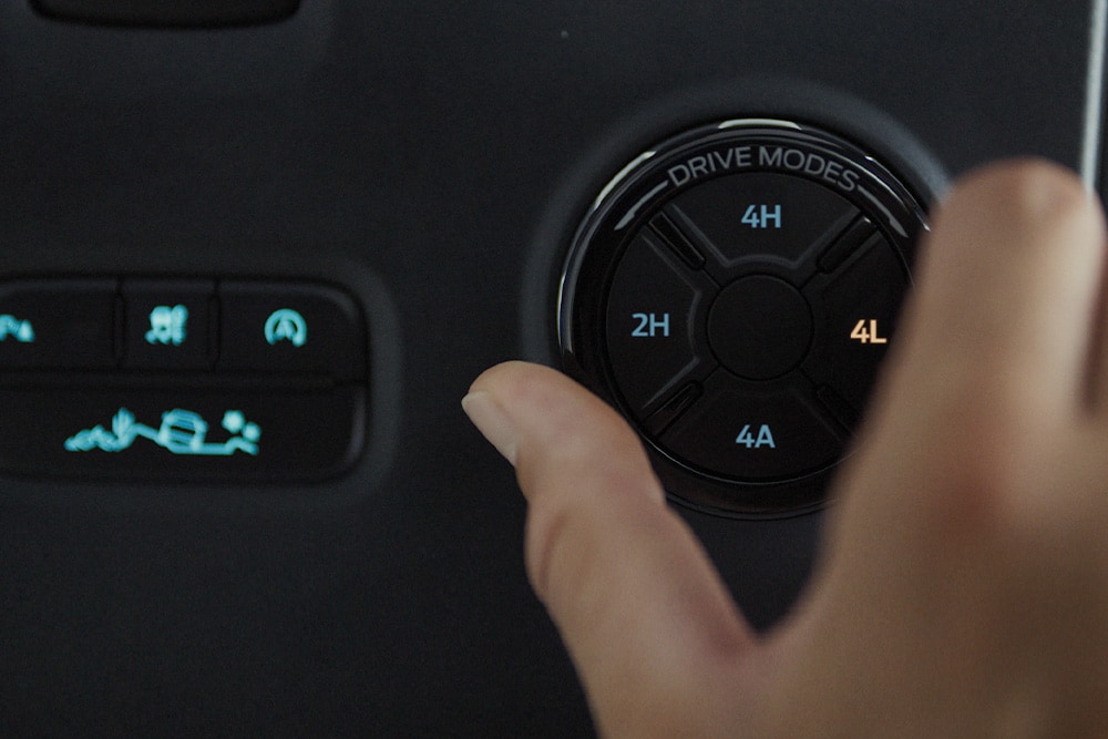 Een hand selecteert een rijmodus via de keuzeknop van de Ford Ranger.