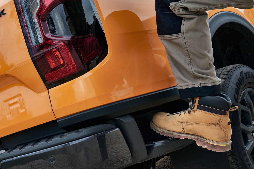 Werknemer stapt op het achterstapje van de Ford Ranger Wildtrak.