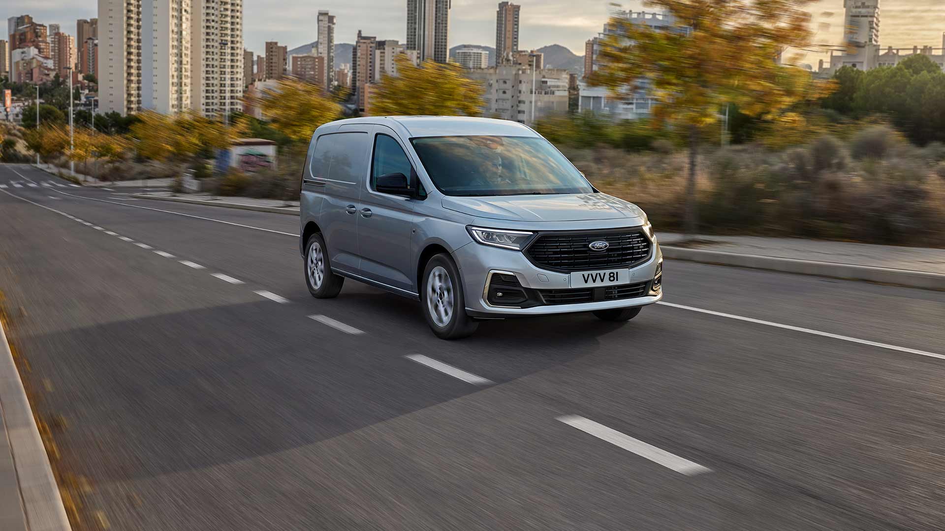 Een Ford Transit Connect rijdt in een stad, met verchroomde mistlampranden en automatische koplampen.