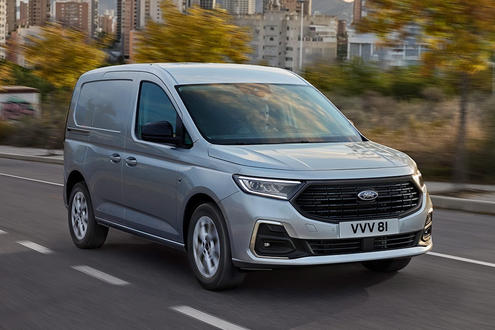 Een Ford Transit Connect rijdt in een stad, met verchroomde mistlampranden en automatische koplampen.