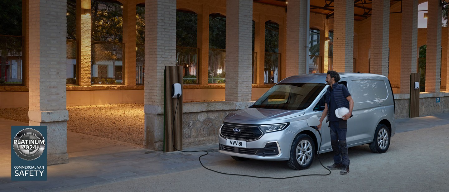 Een man met een helm steekt een laadkabel van een wallbox in de nieuwe Ford Transit Connect in Stardust Silver.