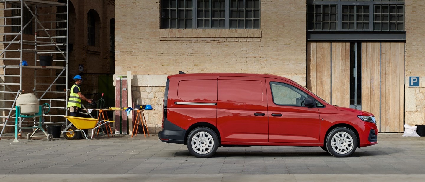 Nieuwe Ford Transit Connect in Maple Red met zijlaaddeur, geparkeerd aan een bouwplaats.
