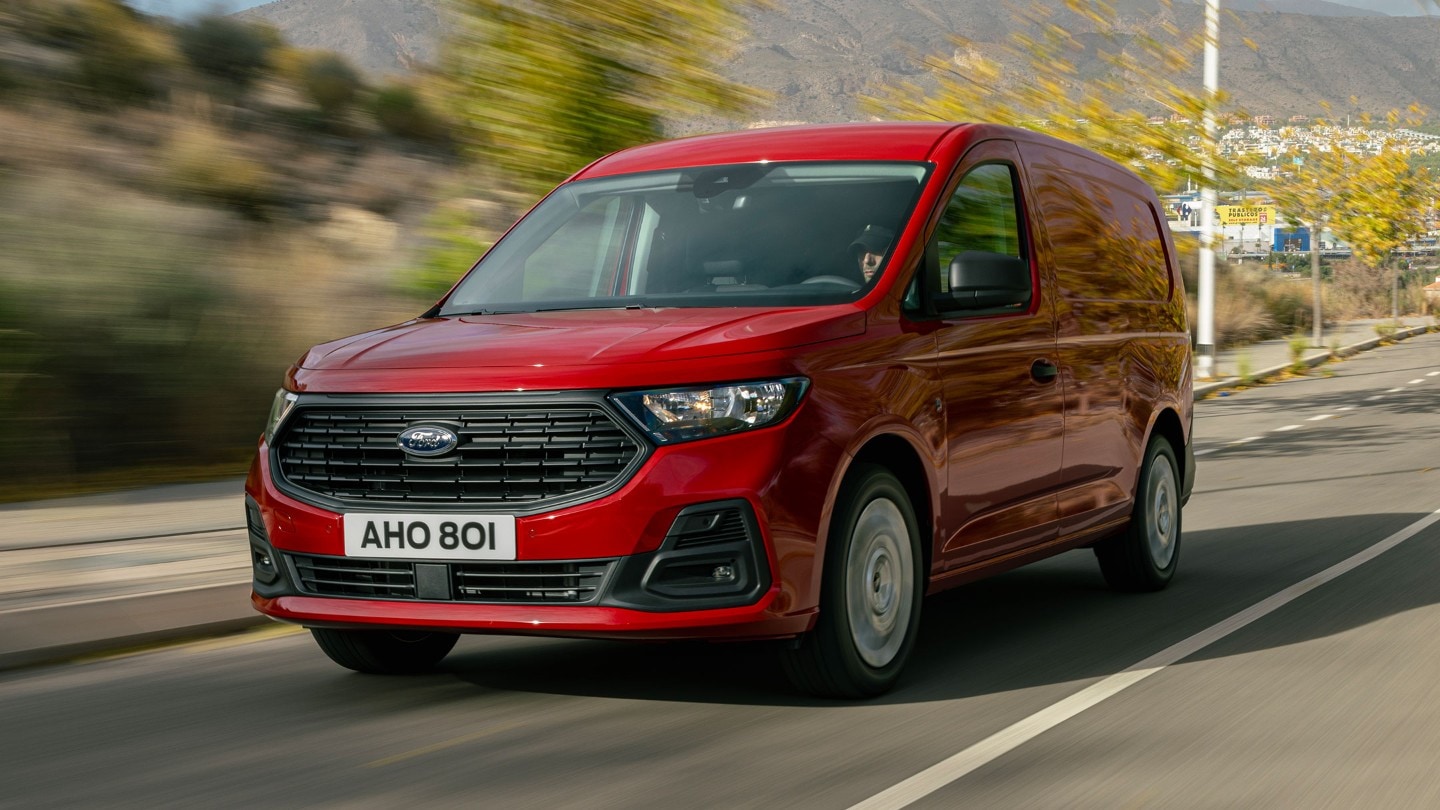 Nieuwe Ford Transit Connect met voorgrille en koplampen in Maple Red rijdt langs een weg. 