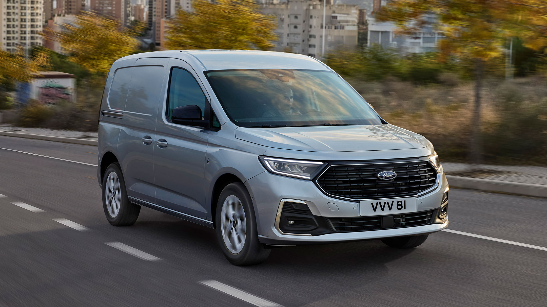 Nieuwe Ford Transit Connect Limited in Stardust Silver met verchroomde buitenkant en automatische koplampen rijdend over een weg. 