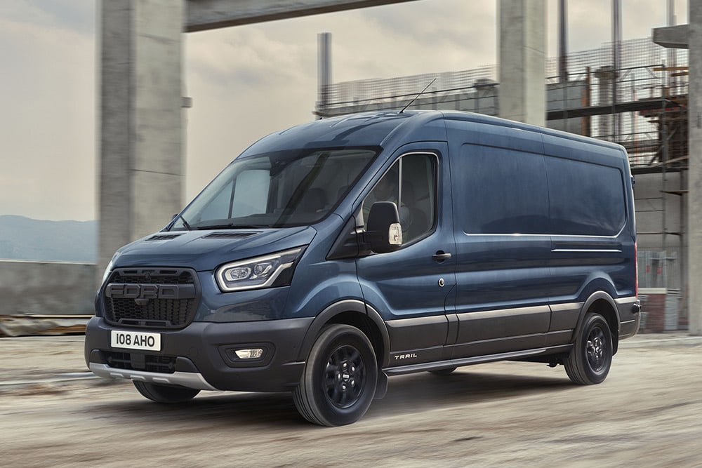 Ford Transit bestelwagen met optionele Trail Pack rijdend op een industrieterrein. 