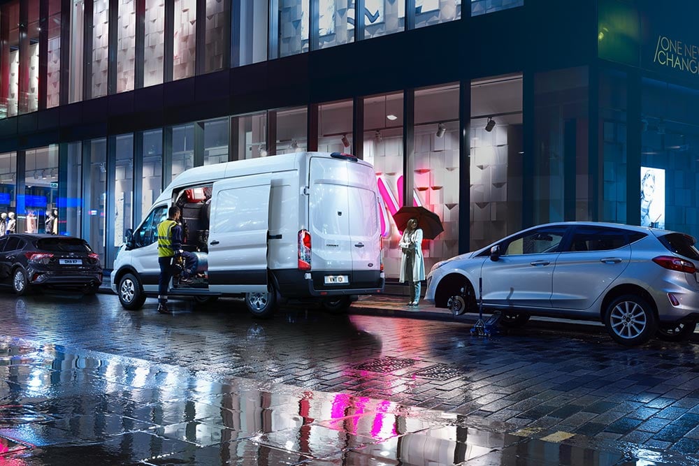 Ford Transit bestelwagen staat in het donker in een stad geparkeerd.