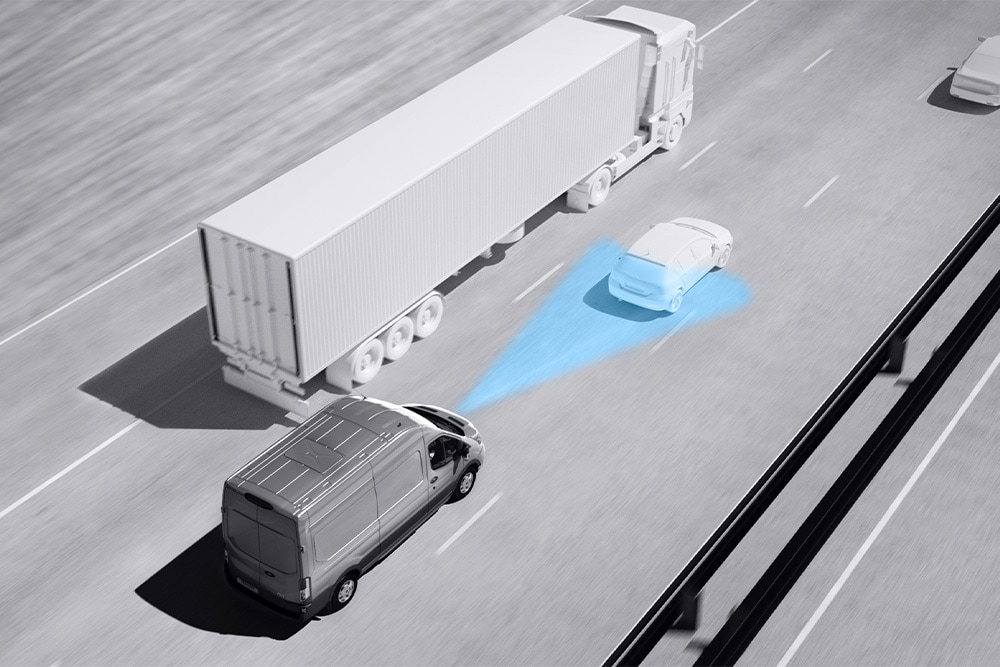 Grijze tekening van een Ford Transit bestelwagen met blauwe lijnen op de weg die het gebruik van geavanceerde rijhulpsystemen weergeven.