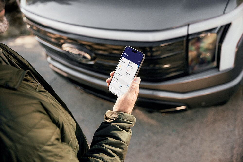 Een man bekijkt zijn smartphone voor een Ford Ranger.