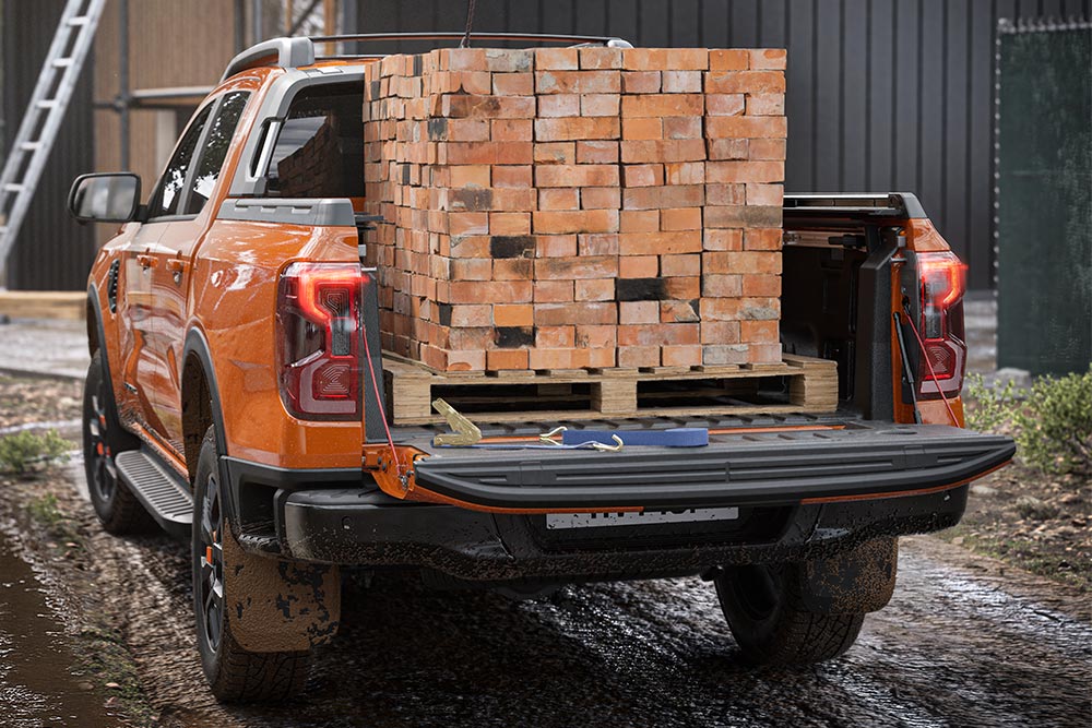Weergave van de achterkant van een oranje Ford Ranger met een stapel bakstenen op de laadbak.