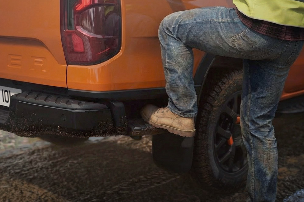 Werknemer stapt op het achterstapje van de Ford Ranger Wildtrak.