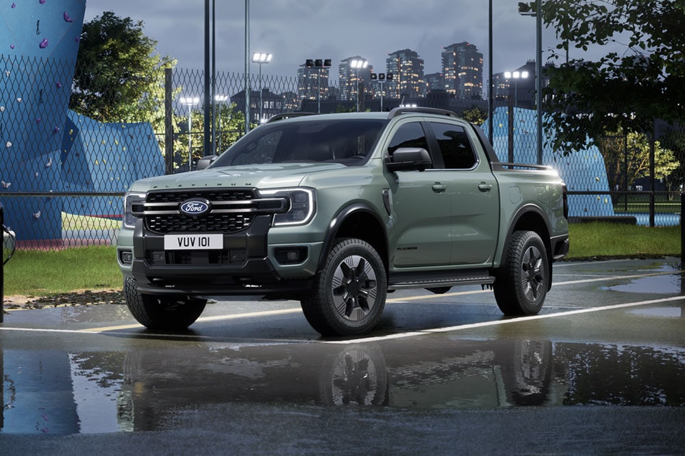 Grijze Ford Ranger PHEV geparkeerd voor een stadsgezicht in de schemering.