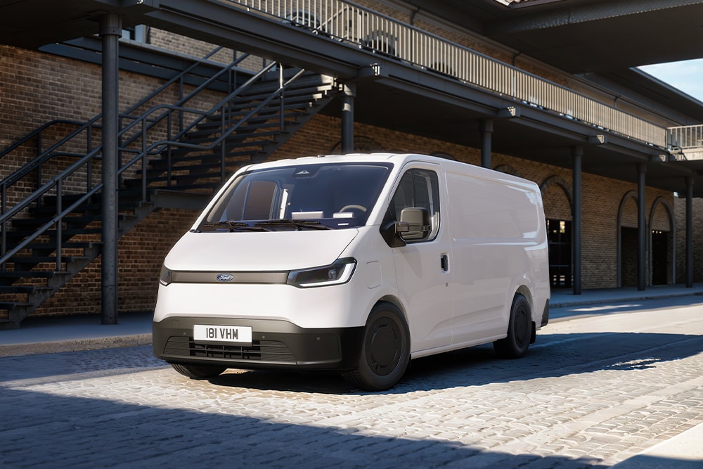 Witte Ford Transit City® L1H1-bestelwagen geparkeerd voor een bakstenen gebouw.