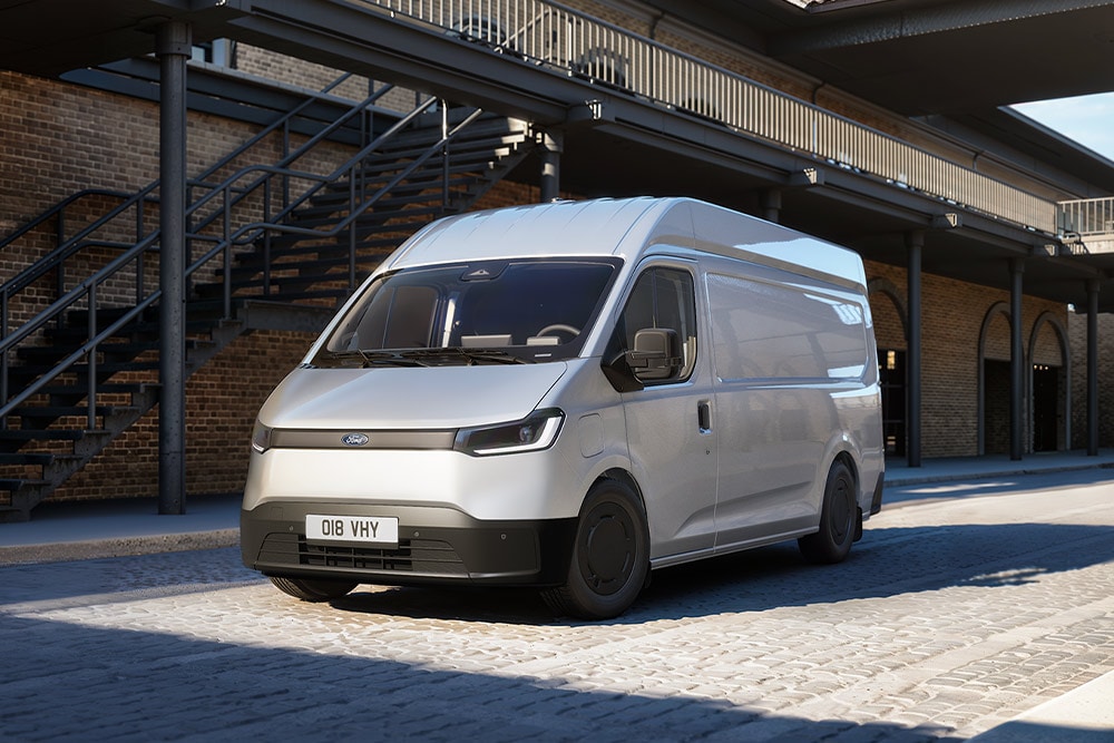 Witte Ford Transit City® L2H2-bestelwagen geparkeerd voor een bakstenen gebouw.