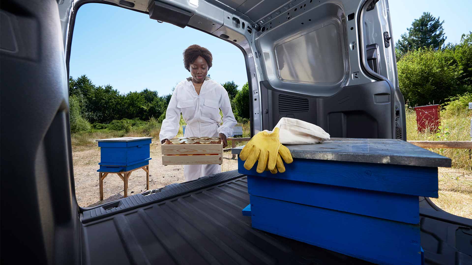 Imker die honing inlaadt in een Ford Transit Courier.