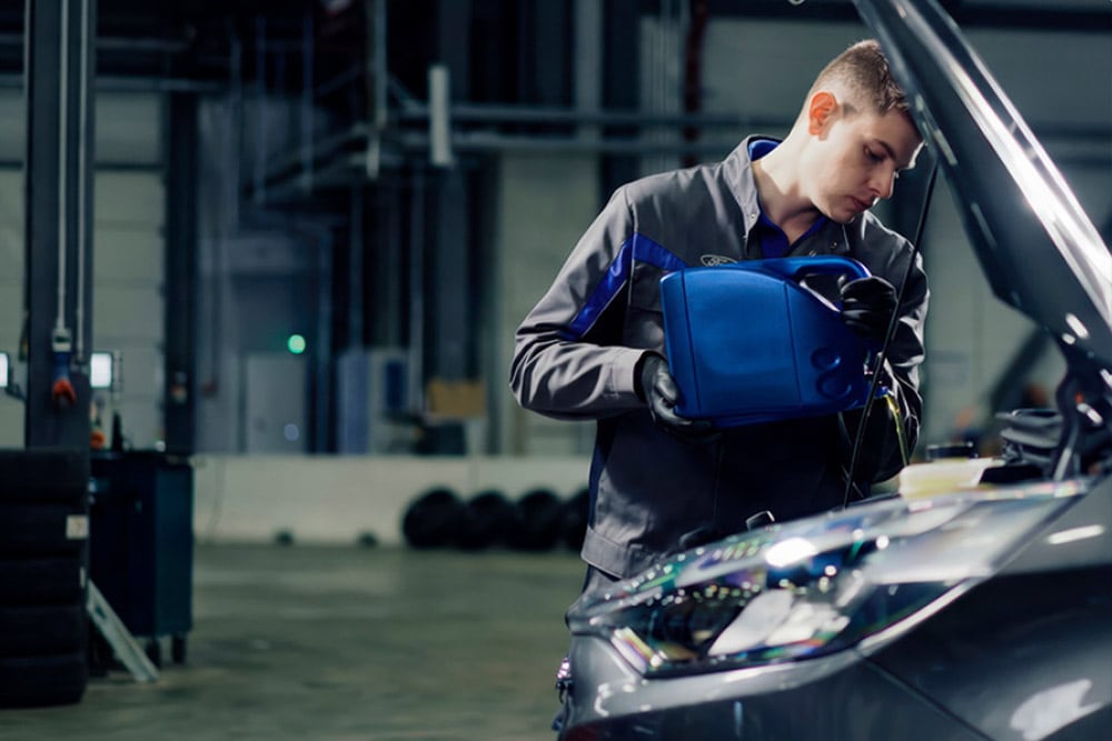 Zijaanzicht van een door Ford erkende technicus die herstellingen uitvoert aan een voertuig in een garage.