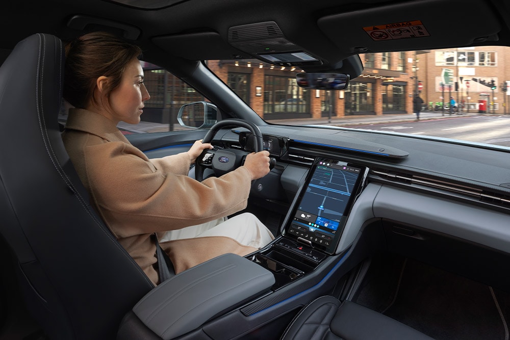 Een persoon die een Ford-voertuig bestuurt, met het grote centrale touchscreen met navigatie.