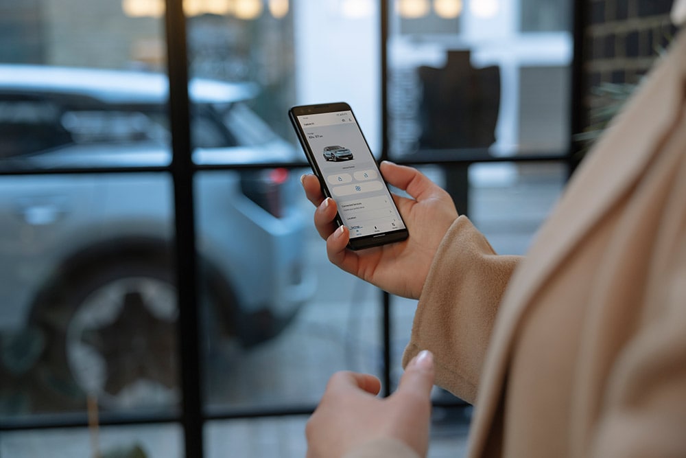 Een persoon met een smartphone toont de FordPass-app met informatie over wagenparkbeheer.