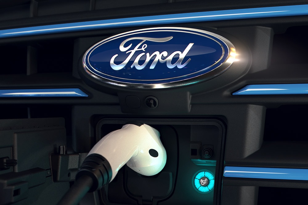 Close-up van een witte oplaadkabel die is aangesloten op de oplaadpoort aan de voorkant van een elektrisch voertuig van Ford.