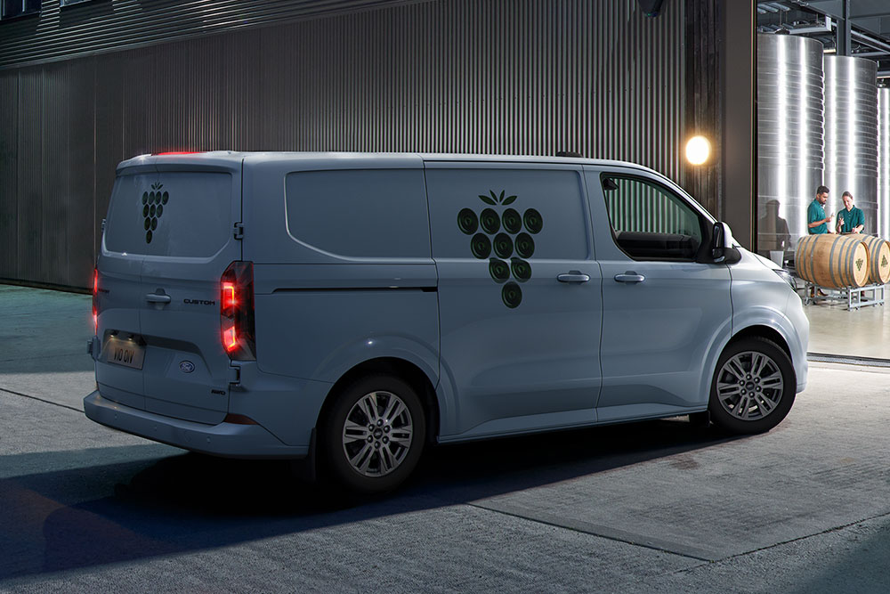 Een witte Ford bestelwagen staat 's nachts geparkeerd voor een magazijndeur.